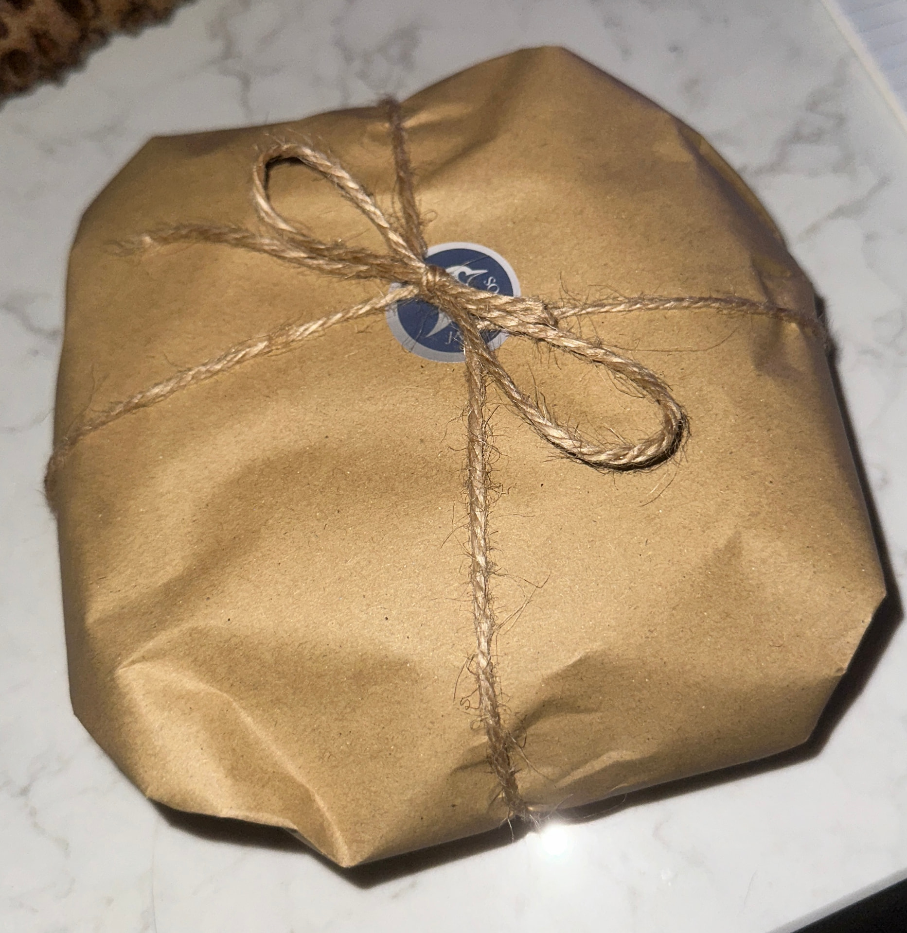 A Jay Studios piece wrapped in kraft paper and tied with jute twine, sealed with the studio sticker