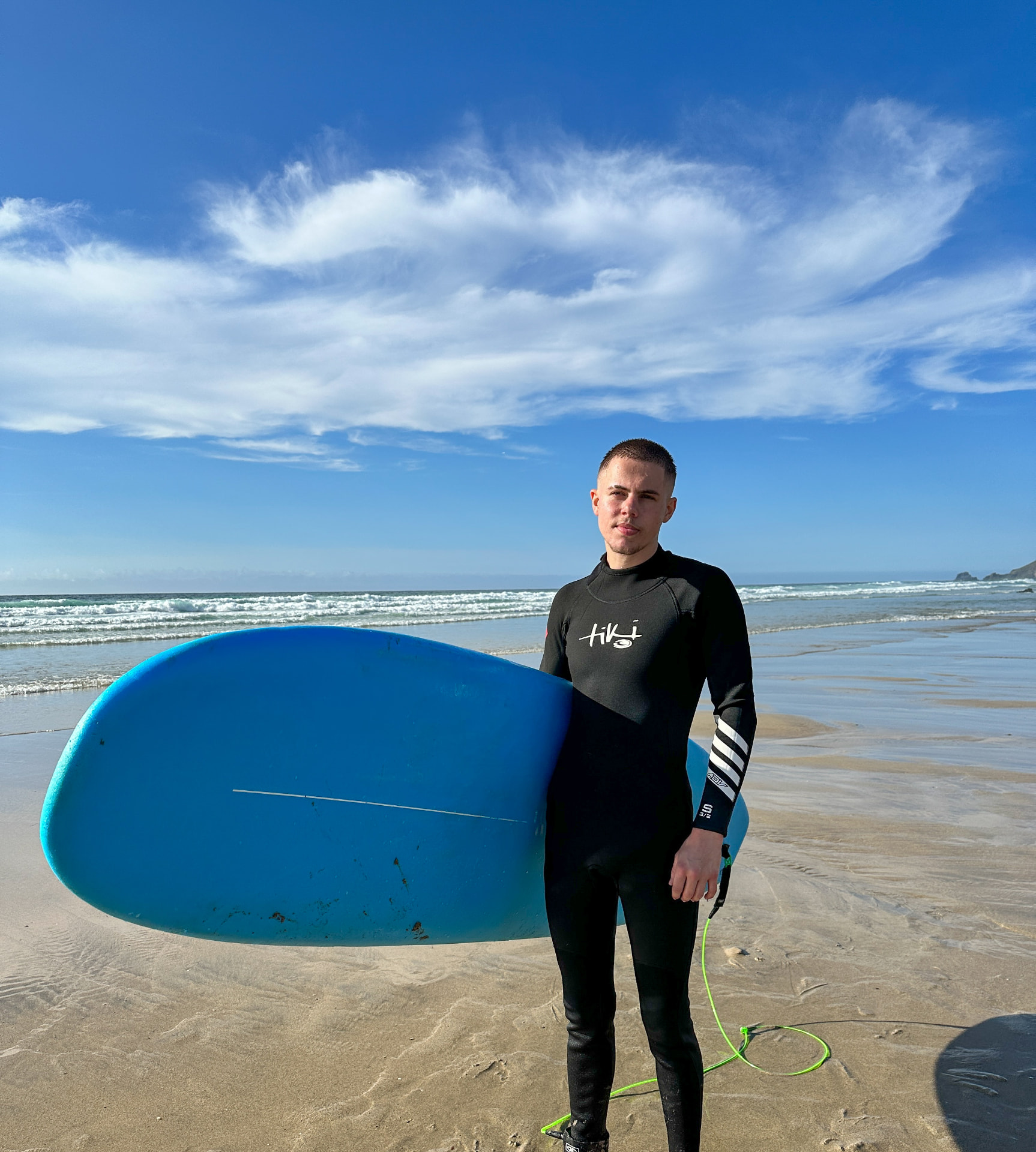 Josh on the beach in Cornwall with a surfboard